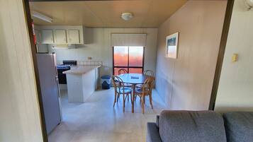 A compact kitchen with a dining area, a sofa, and a window with a view.