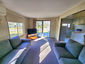 A living room with two sofas, a television, and a sliding glass door leading to a balcony.