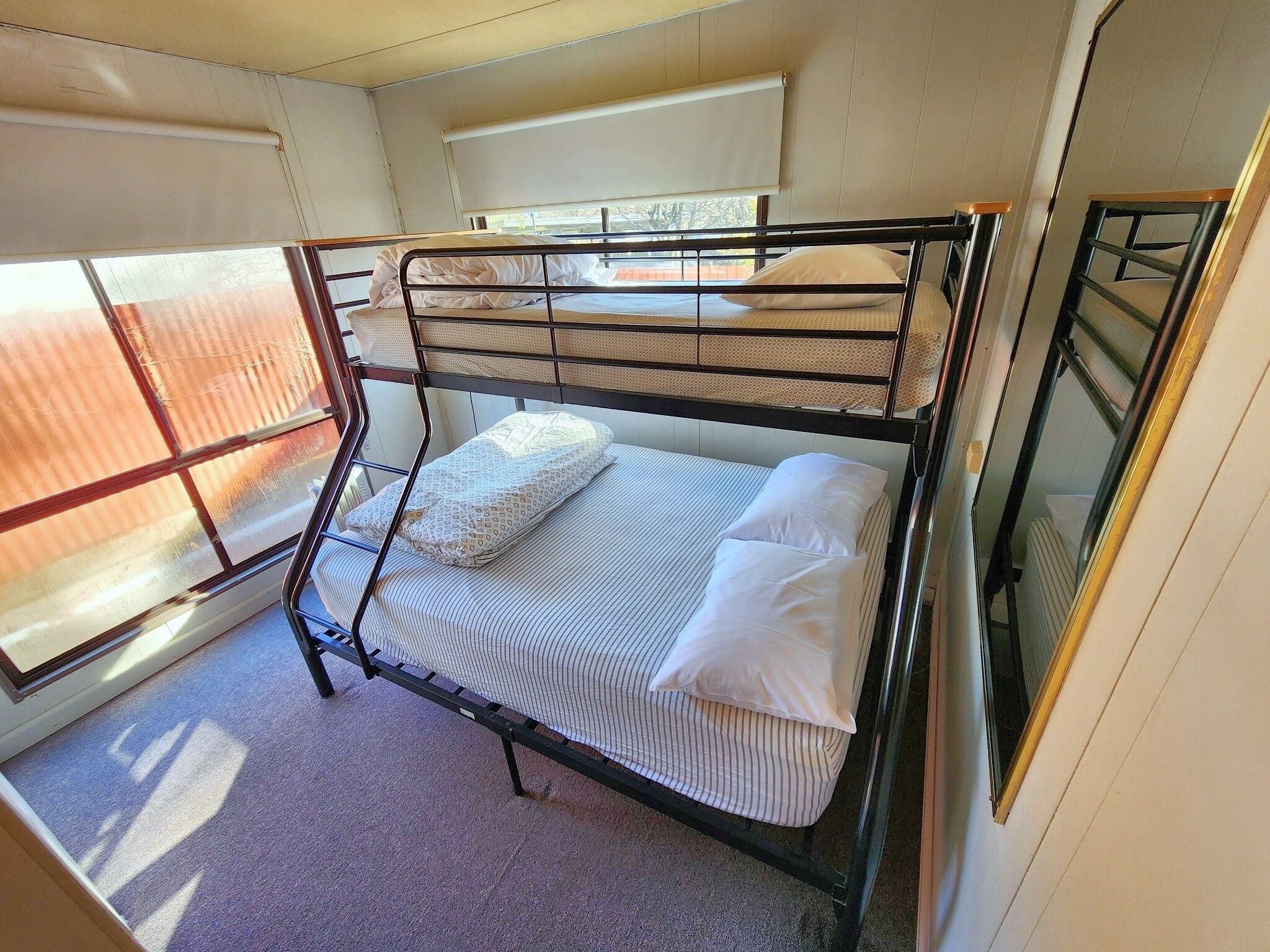 A bunk bed with two levels, a window with a view, and a carpeted floor.