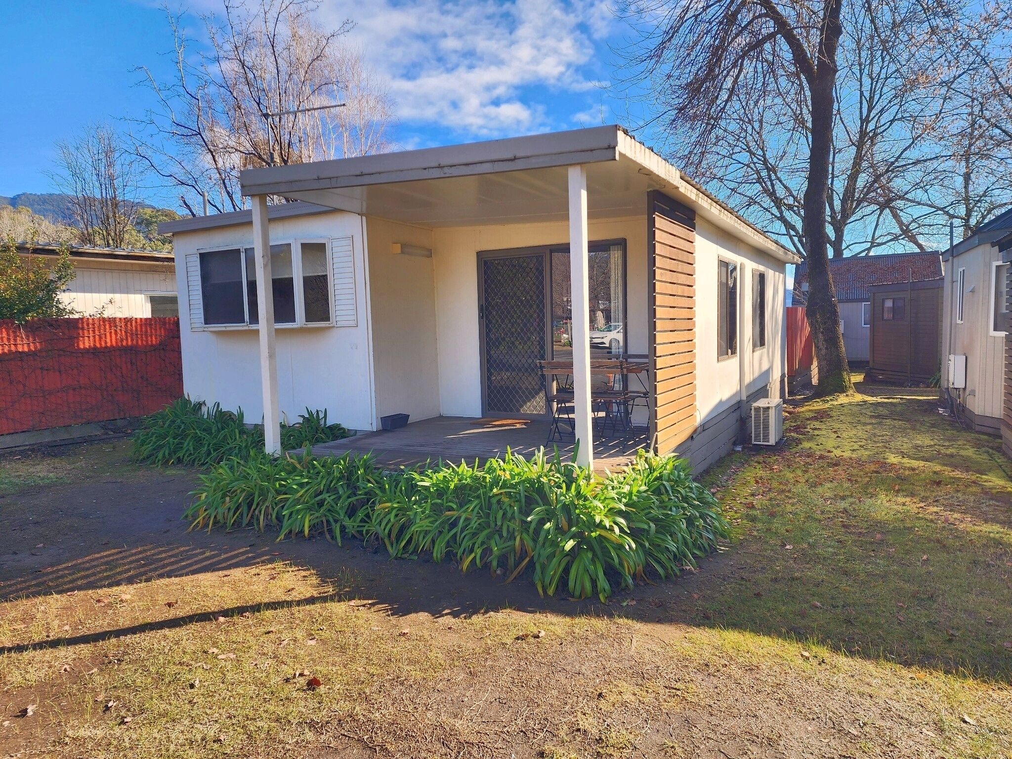 A small, single-story house with a covered porch and a fenced yard.