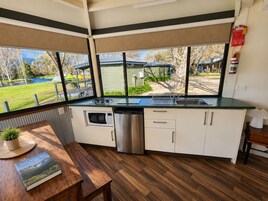Cocina compacta con vistas a un parque, una mesa de comedor con un libro y una pequeña planta en maceta.