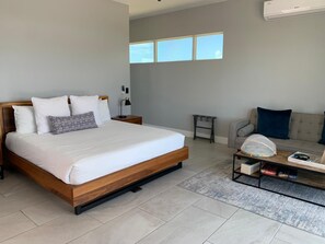 Ein modernes Hotelzimmer mit einem großen Bett, einer Couch, einem Couchtisch und einem kleinen Beistelltisch.