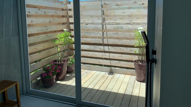 Una terraza de madera con plantas en macetas y una escalera de metal.