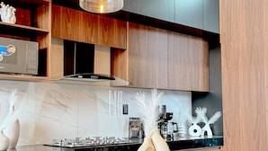 Une cuisine moderne avec un plan de travail en marbre, des meubles en bois et des luminaires suspendus.