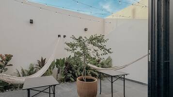 Un patio con dos hamacas, una planta en maceta y piso de baldosas.