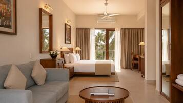 A hotel room with a bed, a sofa, a coffee table, a desk, and a chair.