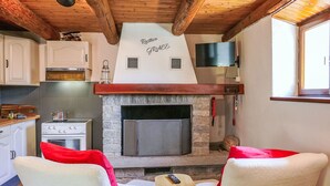 A rustic kitchen with a stone fireplace, white cabinets, and wooden beams. - Rustico Grace by Interhome (Malvaglia)