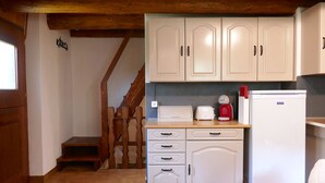 A kitchen with white cabinets, a wooden staircase, and a white refrigerator. - Rustico Grace by Interhome (Malvaglia)
