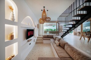 Un salon moderne doté d’un téléviseur à écran plat, d’un escalier et offrant une vue sur l’extérieur.