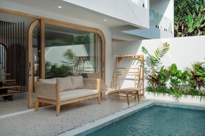 Ein moderner Außenbereich mit Pool, Holzmöbeln und tropischen Pflanzen.