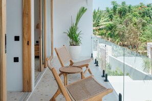 Ein Balkon mit zwei Holzstühlen und einem Blumentopf, mit Blick auf einen üppigen Garten.