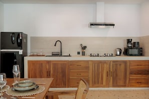 Eine Küche mit Holzschränken, einer Edelstahl-Dunstabzugshaube, einem Kühlschrank und einer Kaffeemaschine.