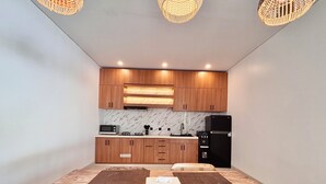 A modern kitchen with wooden cabinets, a black refrigerator, and a microwave. - Private Two Bedroom Pool Villa, Spacious Garden and Tranquil (Ubud)