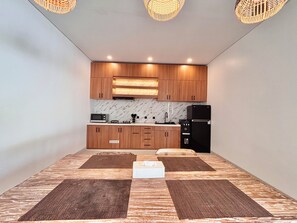 A modern kitchen with wooden cabinets, a black refrigerator, and a microwave. - Private Two Bedroom Pool Villa, Spacious Garden and Tranquil (Ubud)