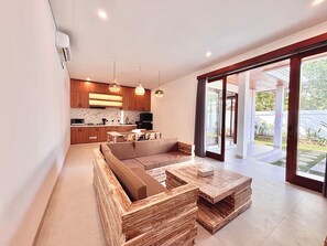 A modern interior with a kitchen, dining area, and a large sliding glass door leading to an outdoor space. - Private Two Bedroom Pool Villa, Spacious Garden and Tranquil (Ubud)
