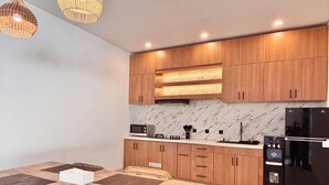 A modern kitchen with wooden cabinets, a marble backsplash, and a black refrigerator. - Private Two Bedroom Pool Villa, Spacious Garden and Tranquil (Ubud)