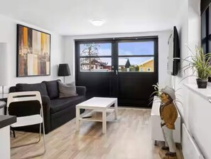 A modern living room with a black sofa, white coffee table, and a painting on the wall. - 4 Star Holiday Home in Otterup (Otterup)