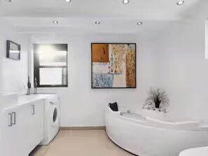 Ein modernes Badezimmer mit einer weißen Badewanne, einer Waschmaschine und einem großen Fenster.