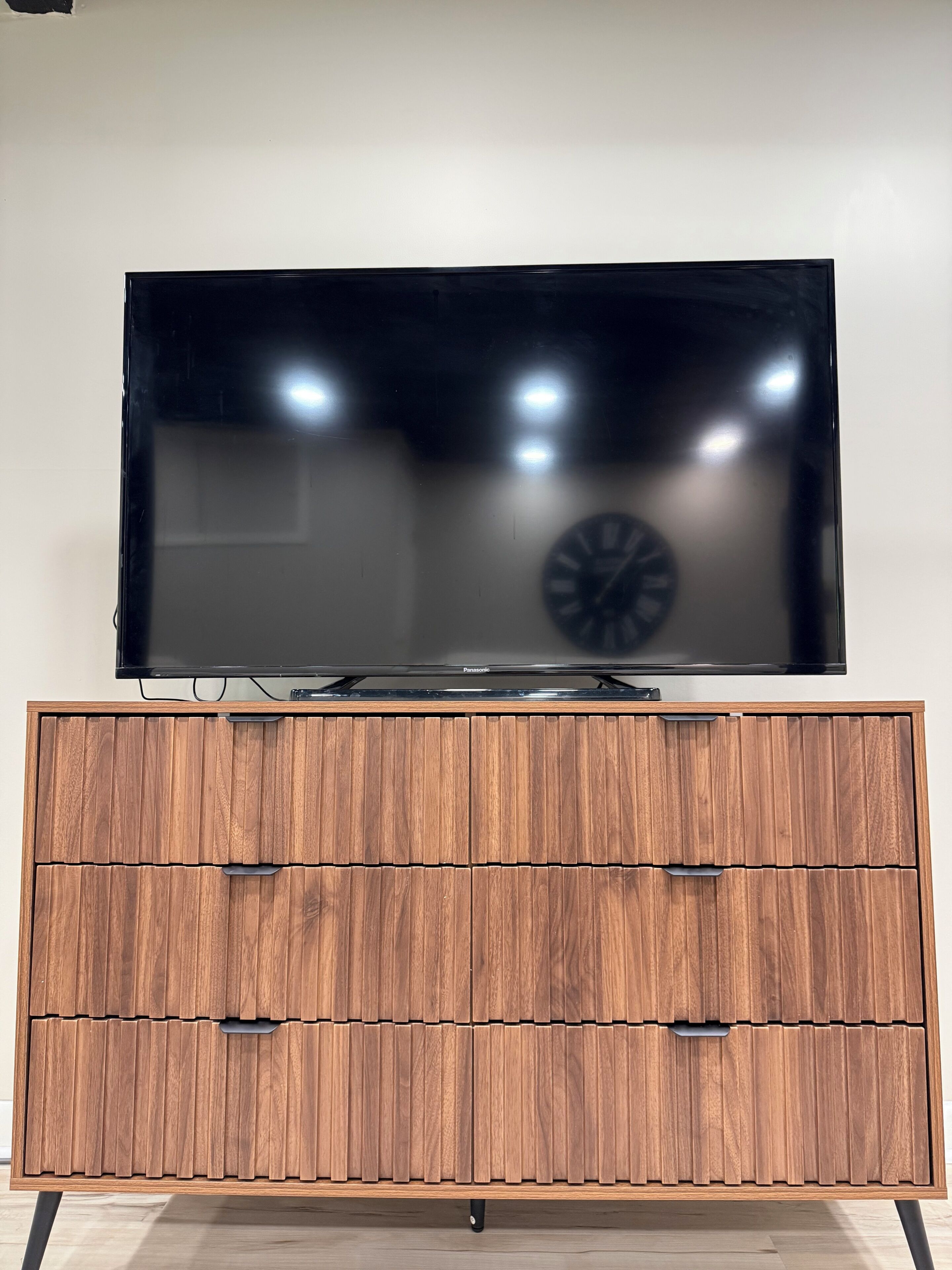 A flat-screen TV on a wooden cabinet with drawers.