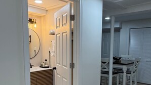 Ein Flur mit einem Badezimmer, einem Essbereich und einem gemusterten Teppich.
