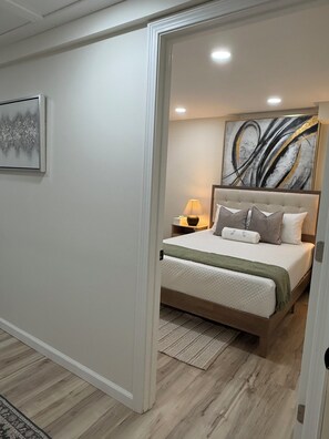 A bedroom with a bed, a nightstand, a lamp, and a large abstract painting on the wall. - The Modern Garden Suite: With Private Entrance ~ 1 BR - sleeps 3 (Manchester)