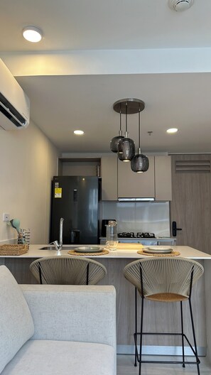 A modern kitchen with a central island, bar stools, and pendant lighting. - Luxury Stay in Santa Marta, Beach & Pools (Magdalena)