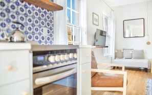 A modern kitchen with a stove, oven, and a blue patterned backsplash. - Park House, Studio 3A on Monterey Square (Savannah)