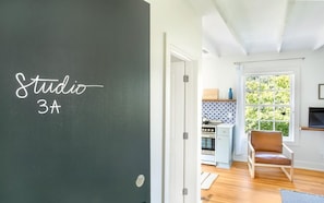 A room with a chalkboard labeled 'Studio 3A' and a view into a kitchen with a stove and a chair. - Park House, Studio 3A on Monterey Square (Savannah)
