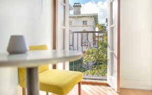 A balcony with a view of a building, a table with a chair, and a vase. - Park House, Studio 3A on Monterey Square (Savannah)
