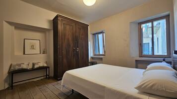 Un dormitorio con cama, armario de madera, banco y ventana.