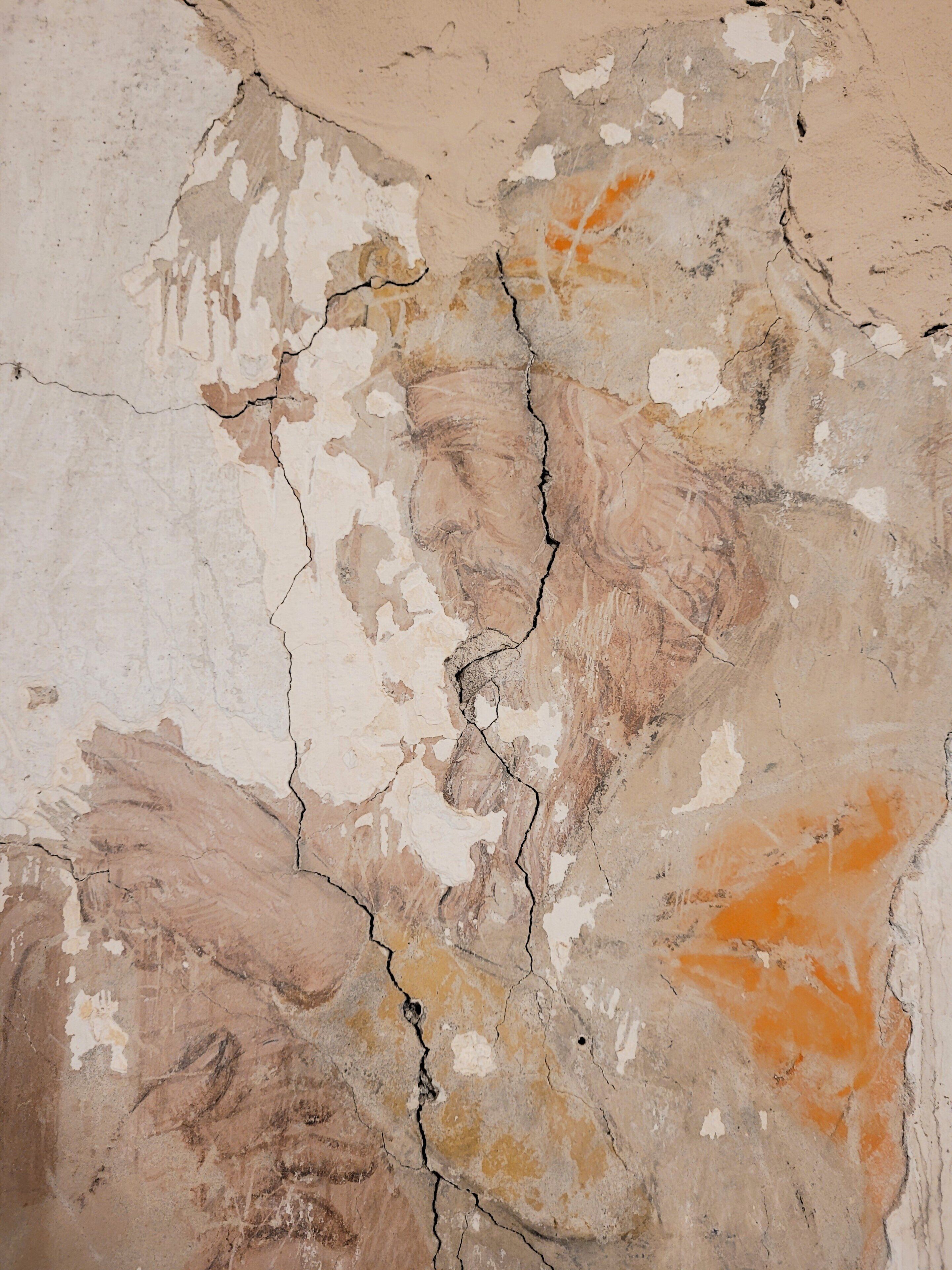 Eine strukturierte Wand mit deutlichen Rissen und abblätternder Farbe.