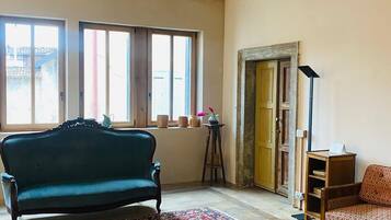 A room with a large bed, a sofa, a small table, and a window with curtains.