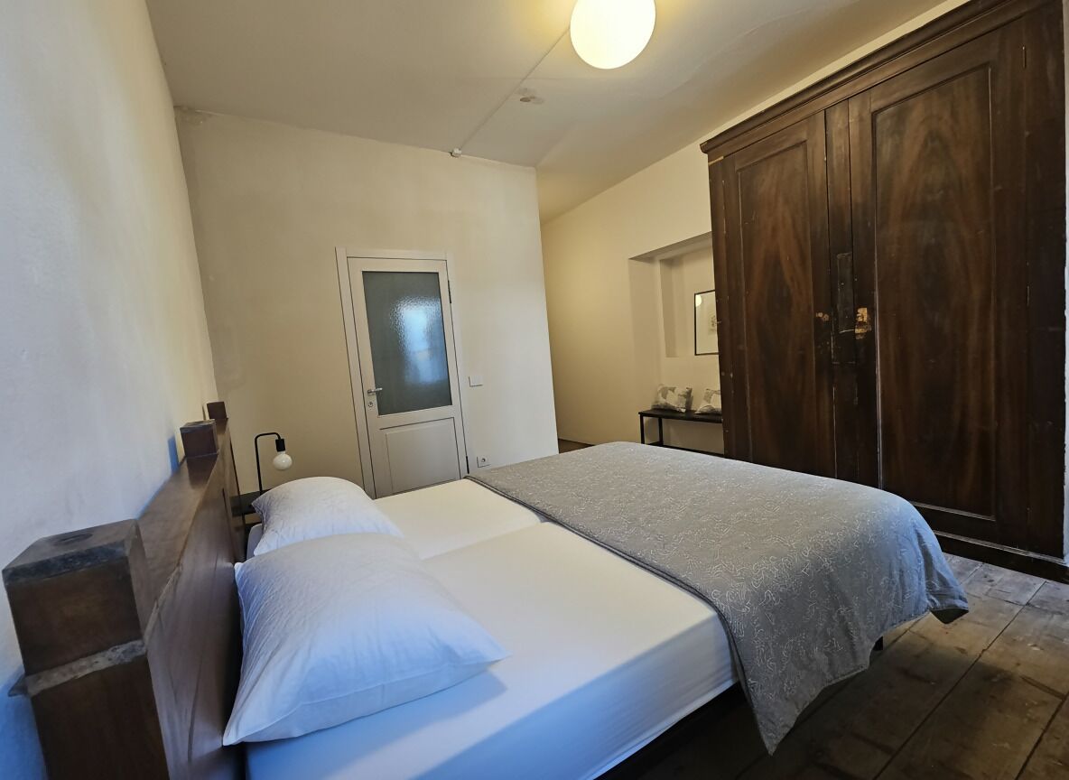 A bedroom with a bed, a wardrobe, a door, and a light fixture.