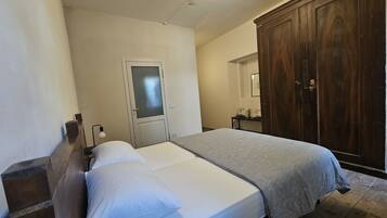A bedroom with a bed, a wardrobe, a door, and a light fixture.