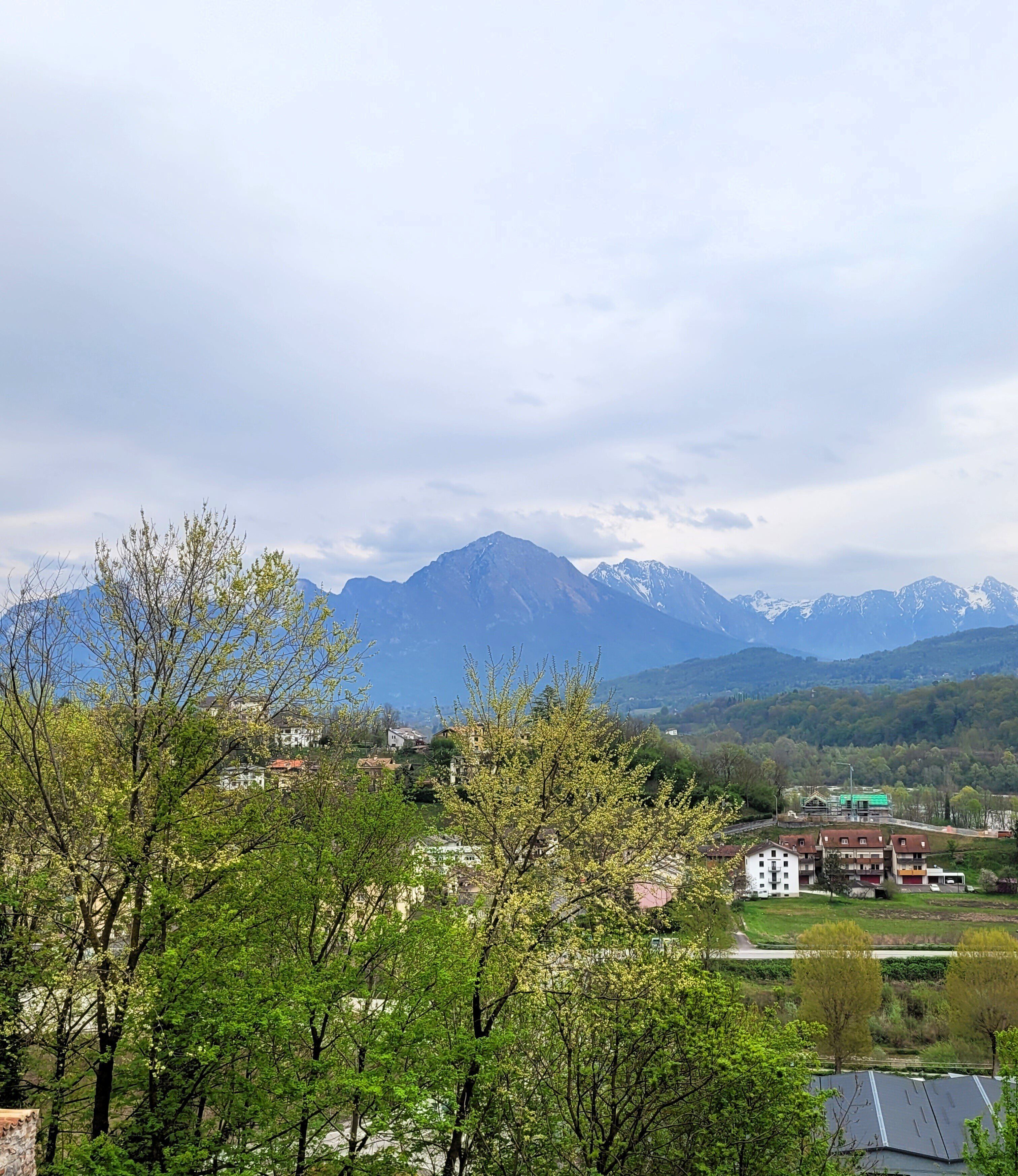 A mountainous landscape with buildings in the foreground and snow-capped peaks in the background.