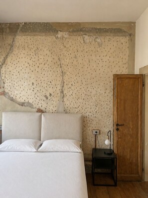 Une chambre à coucher avec un lit, une porte en bois et une petite table avec une lampe.