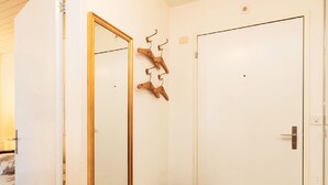 Una habitación con puerta de madera, un espejo con marco de madera, un taburete y un barril de madera.
