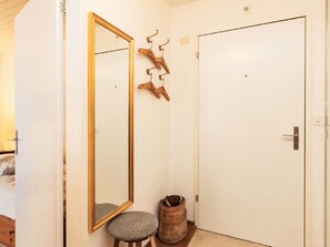 Ein Zimmer mit Holztür, einem Spiegel mit Holzrahmen, einem Hocker und einem Holzfass.