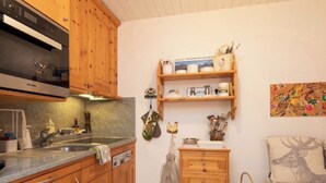 Una cocina compacta con armarios de madera, horno integrado y lavamanos.