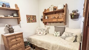 Un dormitorio con una cama, un aparador, estantes con diversos objetos y un cuadro colgado en la pared.