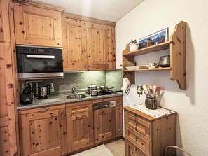 A kitchen with wooden cabinets, a stainless steel microwave, a sink, and a stove. - Skyline Apartment 203 on Lake St. Moritz by Interhome (St. Moritz)