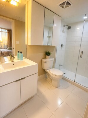 A modern bathroom with a toilet, sink, and shower. - Urban 2BR Retreat | Lake View + Parking + WiFi (Toronto)