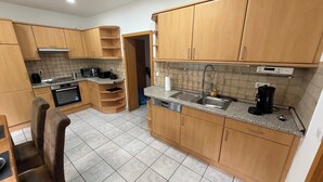 Uma cozinha com armários de madeira, forno embutido, micro-ondas, cafeteira e máquina de lavar louça.