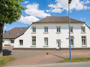 Ein zweistöckiges Gebäude mit Ziegeldach, einem Straßenschild und einer gepflasterten Fläche davor.