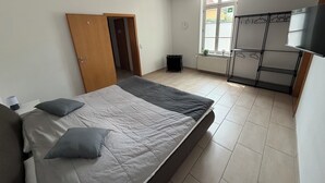 Um quarto com uma cama, um guarda-roupa, um radiador e uma janela.