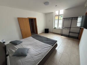 Ein Schlafzimmer mit Bett, Kleiderschrank, Heizkörper und Fenster.