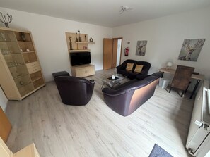 Ein Wohnzimmer mit Sofa, Couchtisch, Fernseher und Bücherregal.