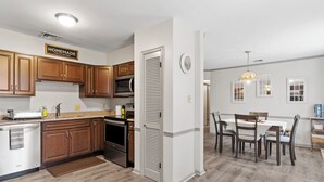 Una cocina moderna con armarios de madera, electrodomésticos de acero inoxidable y un comedor con mesa y sillas.