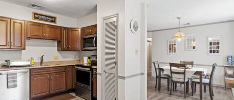 A modern kitchen with wooden cabinets, stainless steel appliances, and a dining area with a table and chairs.