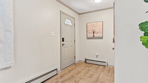 Un pasillo con una puerta blanca, un termostato y un cuadro en la pared.